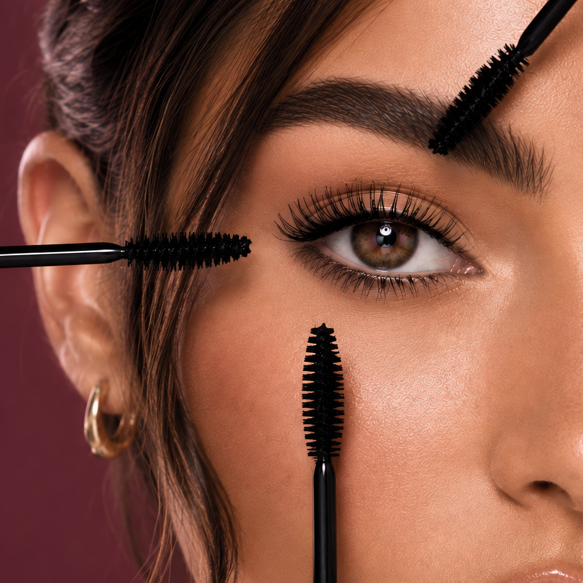 Lash illusion mascara wands held to the lashes of one eye, on her berry ground